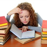 Friendly College student girl with books at the desk isolated
